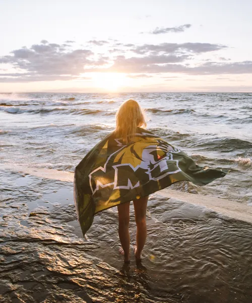 Female student standing in Lake Superior with NMU flag