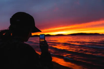 Student taking a photo of a Lake Superior sunset