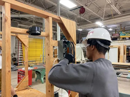 Young man working on an electrical box on a wooden frame in a large shop