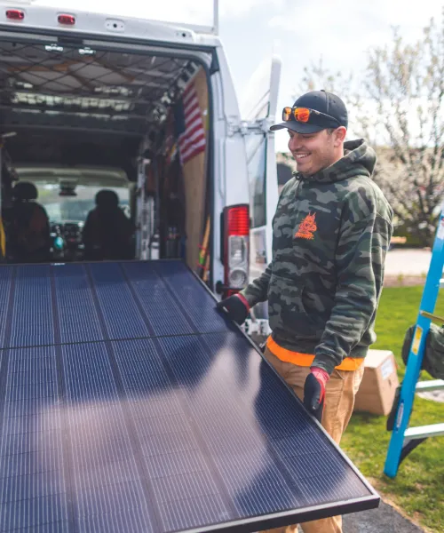 Men carrying a solar panel into the back of a van