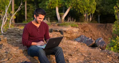 Male student on laptop by Lake Superior