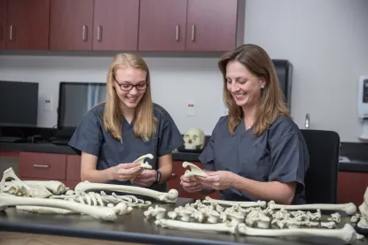 Female professor examining bones with a female student in a lab