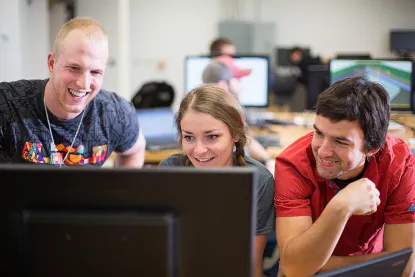 Three students looking at a computer monitor together