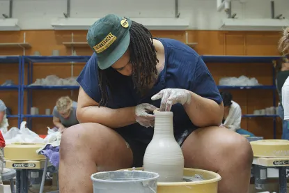 Male student working on a pottery wheel