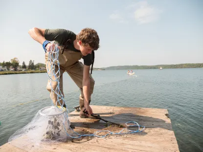 Student throwing fish net into Teal Lake
