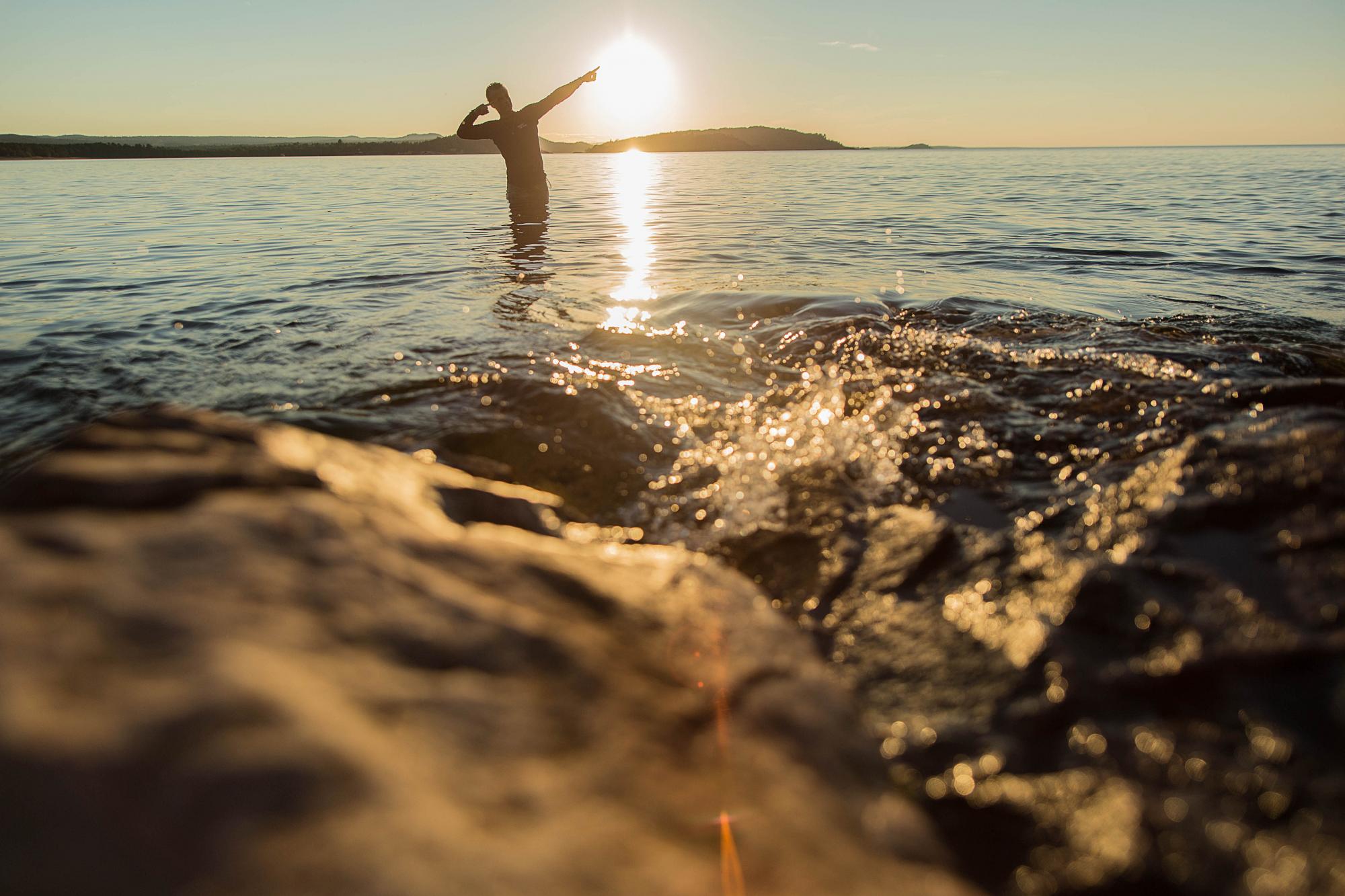 Silhouette of student standing in Lake Superior at sunset