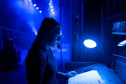 A student wears a headset and reads from a script backstage