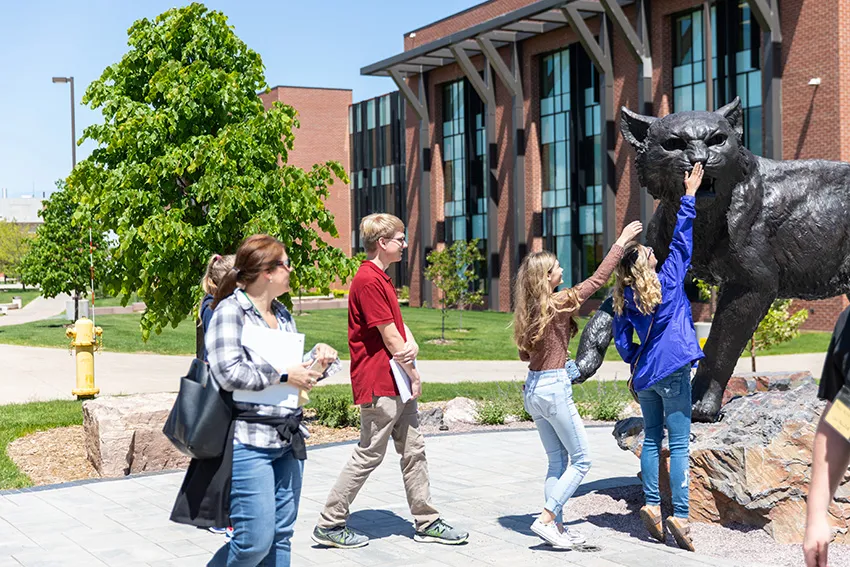 A group of future NMU students at the NMU Wildcat statue outside Jamrich Hall.