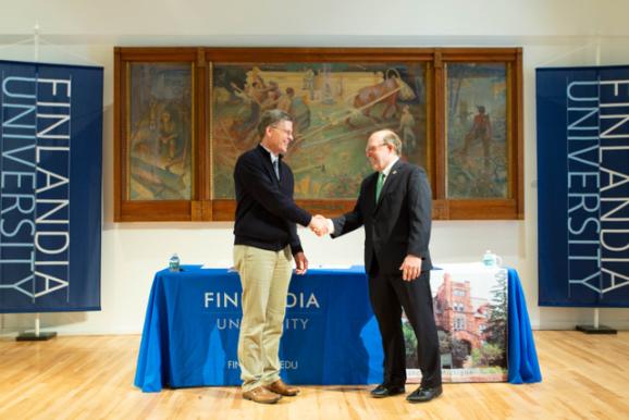 FinnU President Philip Johnson (left) and NMU President Fritz Erickson shake hands