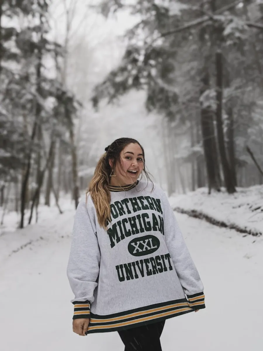 Gwen standing in a magical snowy forest wearing her NMU swag