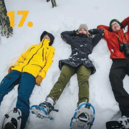 People laying in the snow with snowshoes 