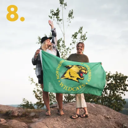 Girls on top of a hill with NMU flag