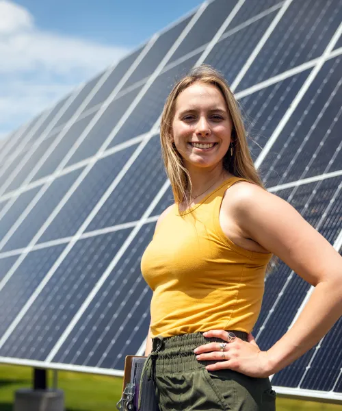 Photo of student standing in front of solar panels.