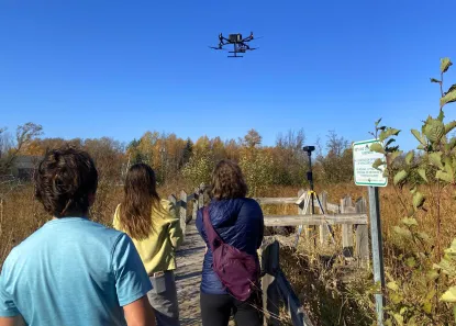 Students observing drone in flight over Presque Isle Mitigation Wetlands