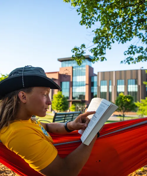 Person reading in a red hammock on NMU campus