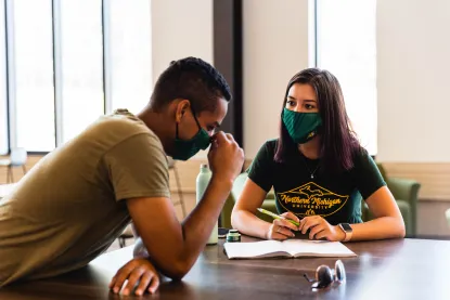 Two students in masks studying indoors