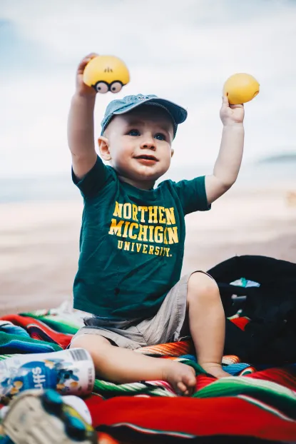 Young child at the beach in NMU t-shirt