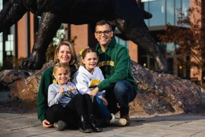 Brock Tessman with his wife and two daughters in front of the wildcat statue