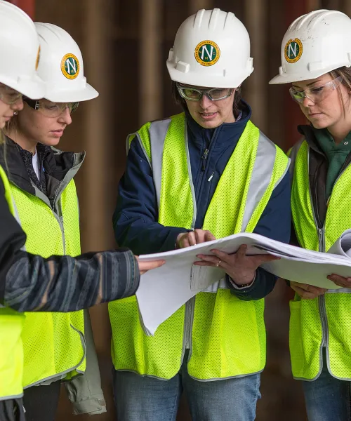 four female construction students looking at construction plans