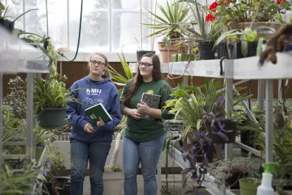 two students walking in a greenhouse