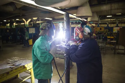 student and instructor welding a pipe