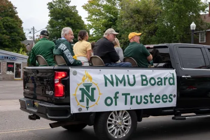 Board of Trustee members riding in the back of a pickup truck in the homecoming parade